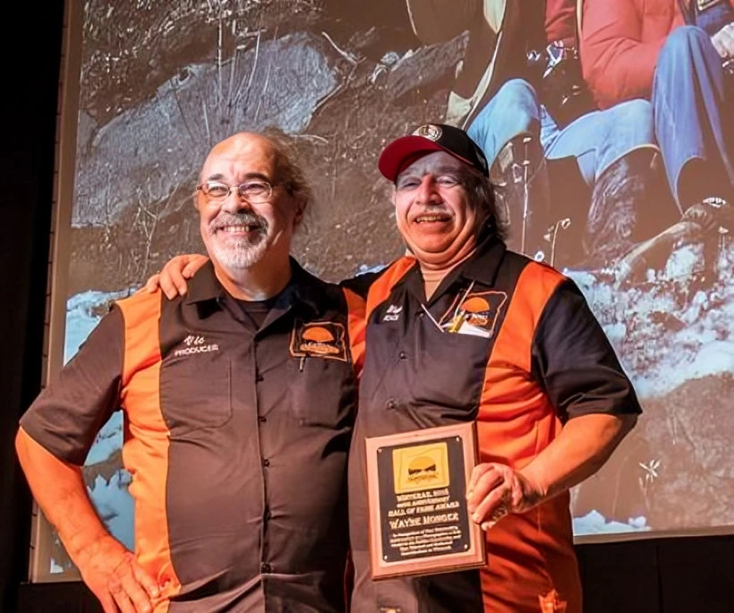 Two men smiling with an award plaque.