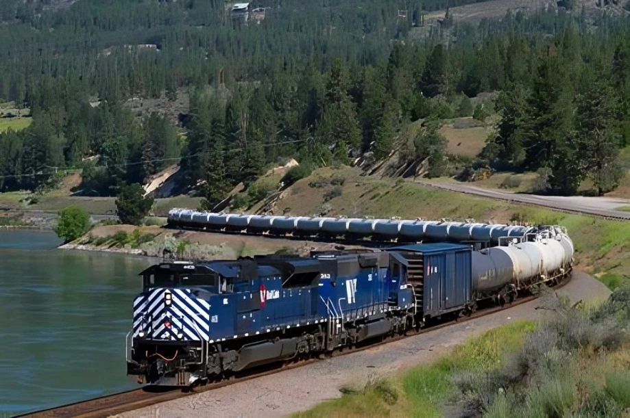 Blue train traveling through scenic forest landscape.