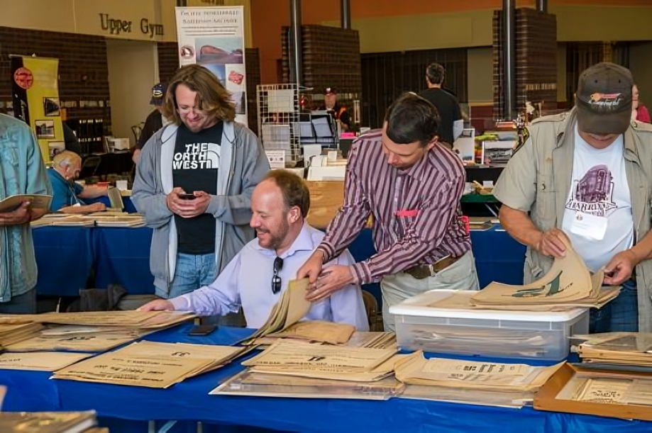 People browsing vintage newspapers at a market.