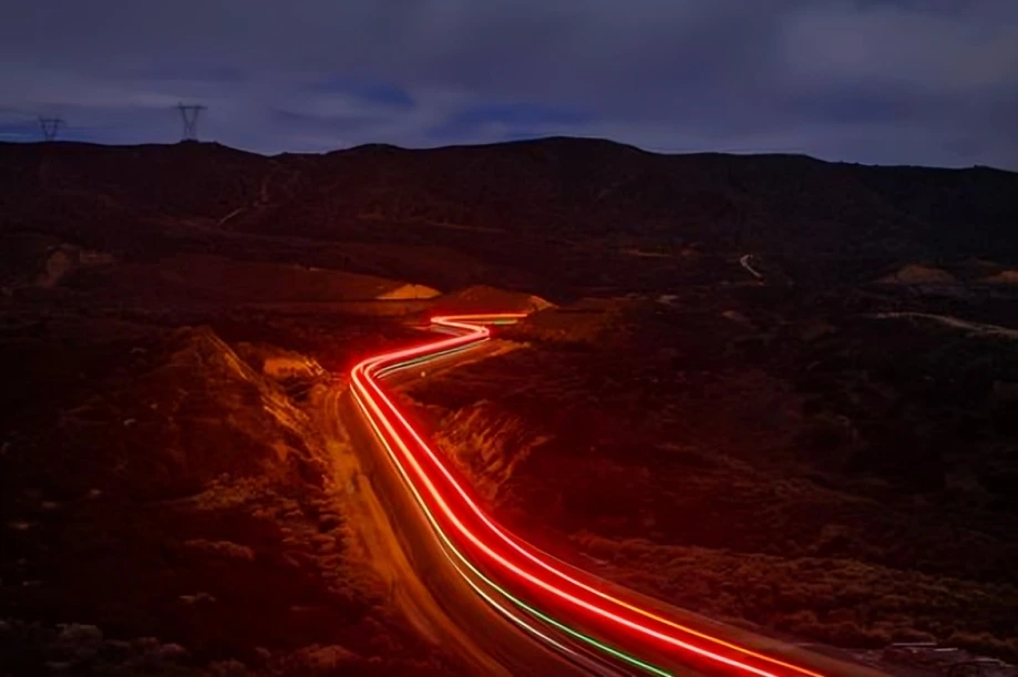 Winding road with red light trails.