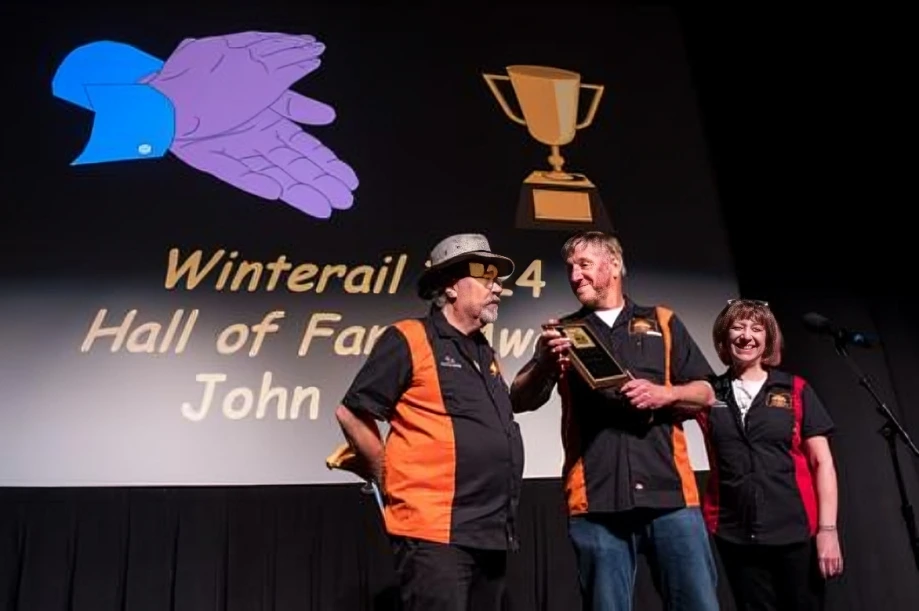 Three people on stage receiving award.
