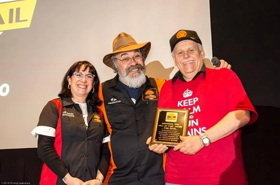 Three people smiling with a plaque award.
