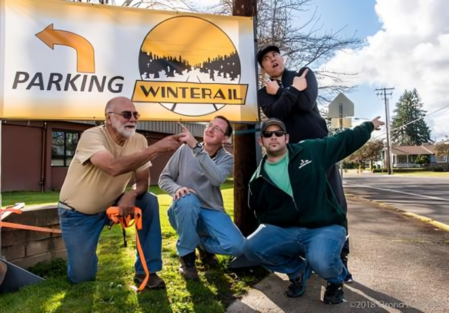 Four people posing by a parking sign.